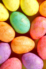 Easter background. Flat lay. Background from bright Easter eggs of different colors. Handmade painted eggs. Close-up, vertical, cropped shot. Easter concept.