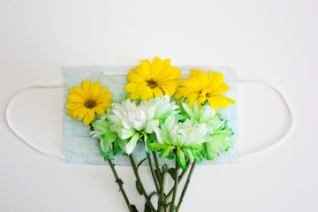Flowers laying in the face mask on white background. Spring time allergy concept.