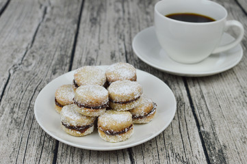 Traditional serbian vanilla cookies with jam, vanilice, on the plate, with cup of coffe in the background