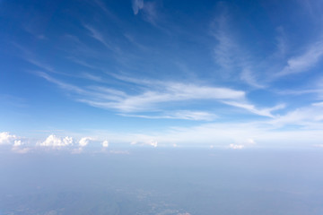 Skyscape view from clear glass window seat from aircraft to cloudscape, traveling on white fluffy clouds and vivid blue sky in a suny day