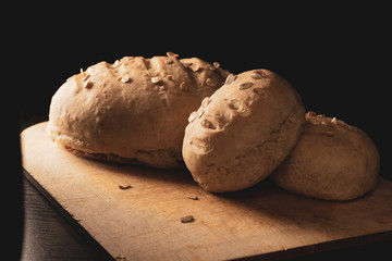 Freshly baked homemade buckwheat flour and whole grain corn bread. Bread sprinkled with oat flakes on a dark background. Healthy gluten free food. Low key photo