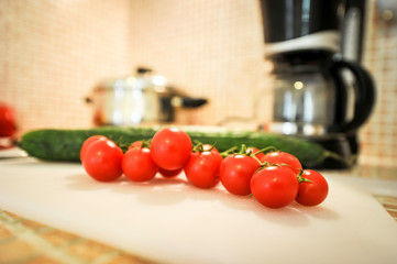A bunch of cherry tomatoes next to cucumber.