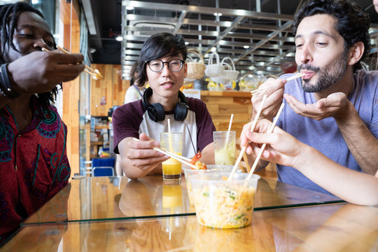 Multiethnic group eating Asian food together in a restaurant