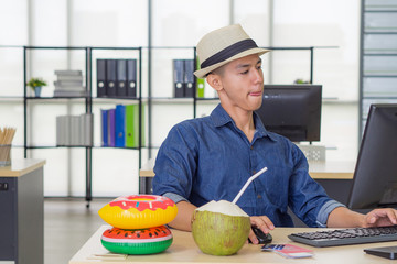 Fototapeta premium Young Asian man wearing a hat and working at the computer while sitting in the office