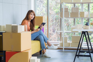 Asian businesswoman holding a tablet and looking camera with a smile while sitting on a sofa in the office