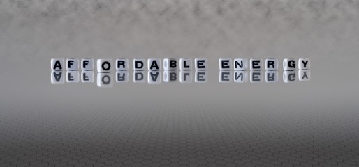 affordable energy concept represented by black and white letter cubes on a grey horizon background...