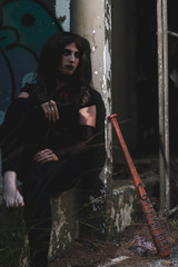 chica vestida de negro con el bate de The Walking Dead, en un descampado y diferentes poses para...
