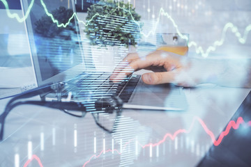 Multi exposure of graph with man typing on computer in office on background. Concept of hard work. Closeup.