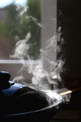 Wok with steam on the stove. Selective focus.