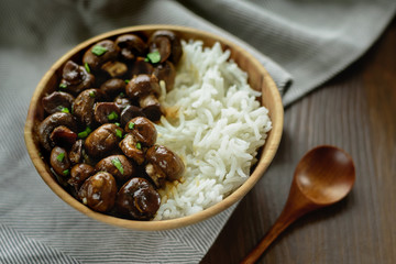 Sauteed white mushrooms with basmati rice in wooden bowl