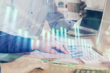 Multi exposure of chart with man typing on computer in office on background. Concept of hard work.