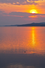 Baikal  Lake in spring morning. Beautiful bright sunrise is reflected in the water of the Small Sea Strait. Dawn waterscape. Natural background