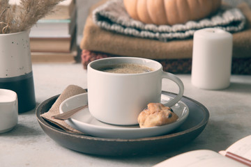 Autumn composition with cup of coffee, books, warm clothes, pumpkin, cookie and candle.
