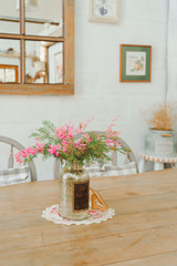 Vintage home decor , pink flower in bottle on wooden table white background.