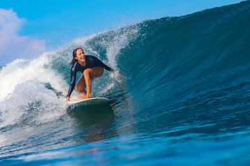 Female surfer on a blue wave - obrazy, fototapety, plakaty