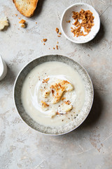 Cauliflower cream soup in bowl with fried onion and parmesan cheese.