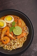 Laksa noodle soup with prawn, egg and bean sprouts. Garnish with lime and mint