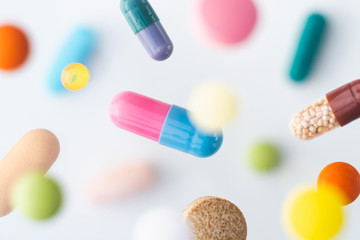 Colorful pills flying above white background, levitation effect