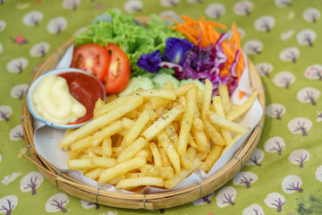 French fries with ketchup and tomato vegetable on tracing paper in basket. Fast food.