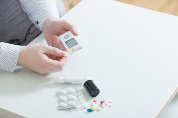 person measures blood sugar with glucometer