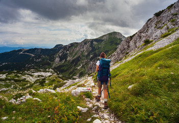 Fototapeta na wymiar Young woman with backpack hiking along the path in the Vogel mountain, Slovenia