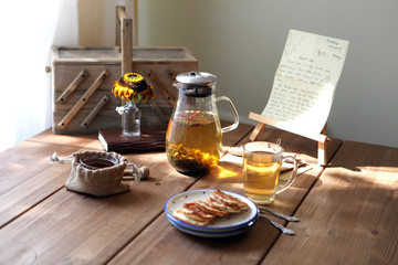 Traditional heral tea with glass teapot, cup, dried rose buds and pancaces . Flowers on wooden table at home background, selective focus, copy space