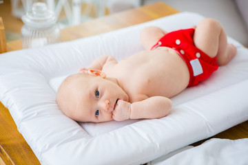 Mother changing reusable diaper or nappy. Reusable diaper and infant. Baby with eco diaper. 