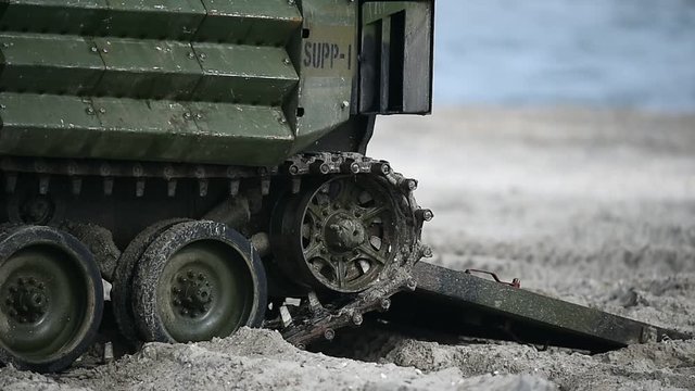 Amphibious army tank caterpillar on a beach in the sand during military exercise 