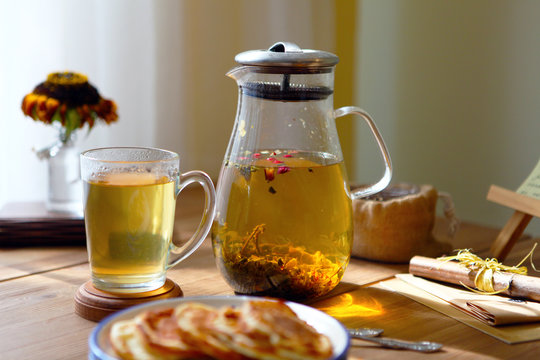 Traditional heral tea with glass teapot, cup, dried rose buds and pancaces . Flowers on wooden table at home background, selective focus, copy space