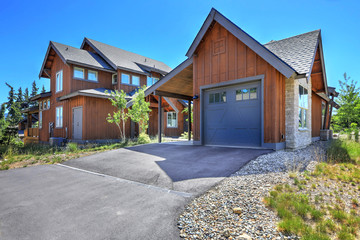 Brown large new wooden  house with harage and blue door.