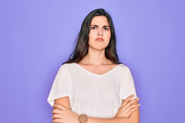 Obraz premium Young beautiful brunette woman wearing casual white t-shirt over purple background skeptic and nervous, disapproving expression on face with crossed arms. Negative person.