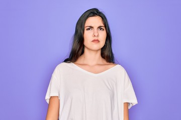 Obraz premium Young beautiful brunette woman wearing casual white t-shirt over purple background looking sleepy and tired, exhausted for fatigue and hangover, lazy eyes in the morning.