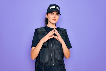 Young police woman wearing security bulletproof vest uniform over purple background Hands together and fingers crossed smiling relaxed and cheerful. Success and optimistic