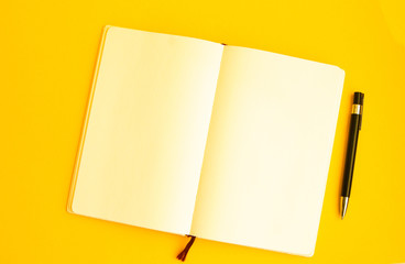 Top view of Blank notebook with pen on yellow background, Freelance working environment view , copy...
