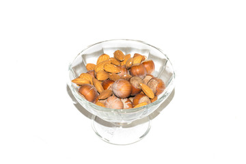 Close up view of shelled hazelnuts and almonds isolated on a white background. A bunch of hazelnuts in a rosette as a background. Macro view of peeled almonds peeled from hazelnuts.