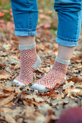 Handmade knitted socks on the background of leaves