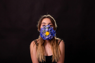 horizontal portrait on black background of a young girl in a mask of flowers