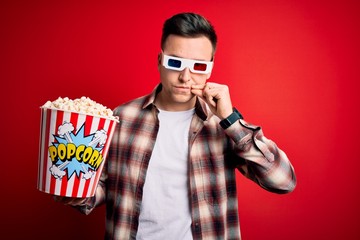 Young handsome caucasian man wearing 3d movie glasses and eating popcorn mouth and lips shut as zip...