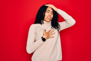 Young african american curly woman wearing casual turtleneck sweater over red background Touching forehead for illness and fever, flu and cold, virus sick