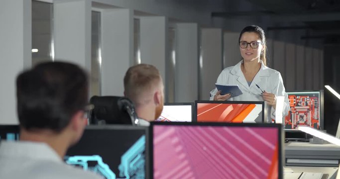 Young female scientist instructing colleagues in office