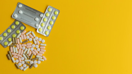 Different pills on the yellow background with copy space