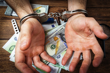 handcuffed hands on a money banknotes background.