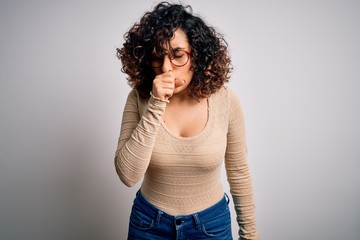 Young beautiful curly arab woman wearing casual t-shirt and glasses over white background feeling unwell and coughing as symptom for cold or bronchitis. Health care concept.