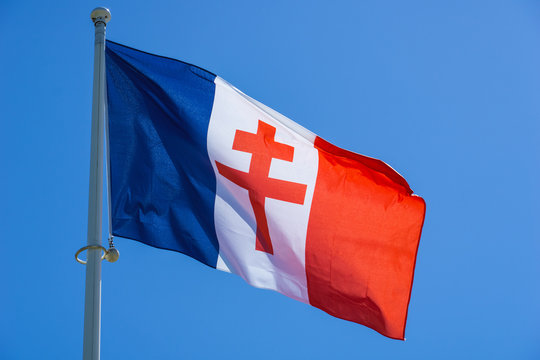 Red Lorraine cross on a waving french flag against blue sky. Général de Gaulle WW2 symbol.