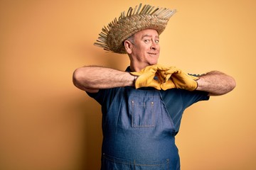 Middle age hoary farmer man wearing apron and hat over isolated yellow background smiling in love showing heart symbol and shape with hands. Romantic concept.