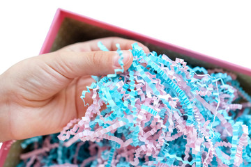 Hand touches paper shavings in a box. Thin Wrapping Paper