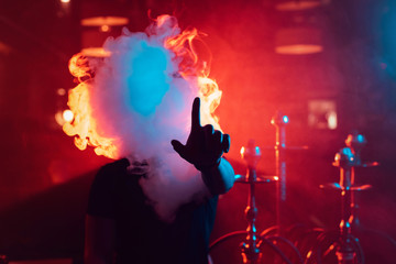 Fototapeta na wymiar man smokes a hookah and lets out a cloud of smoke