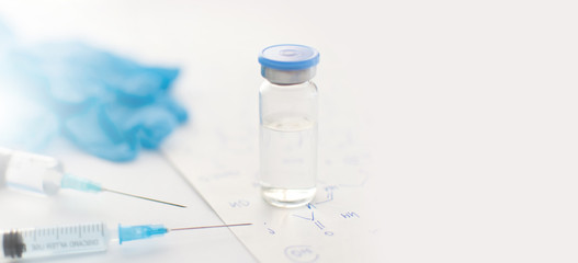 Fototapeta na wymiar Banner with medicine bottle, blue rubber gloves, syringes and paper with handwritten chemical formulas on light background. Coronavirus vaccine development. 2019-nCoV liquid drug, antidote. Copy space