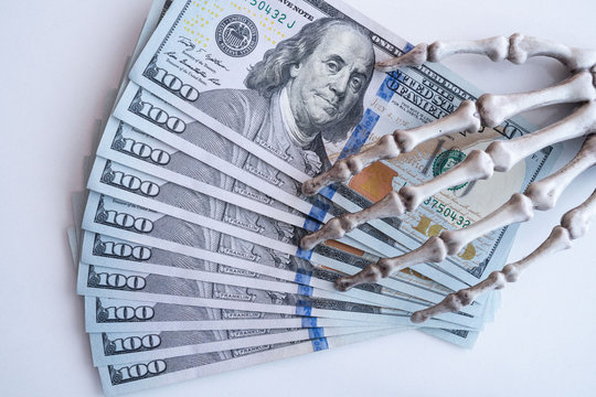 Dollars bills in skeleton hands isolated on white table, money