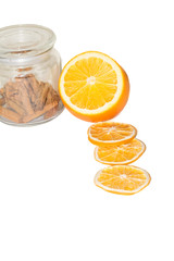 Oranges and cinnamon in a glass jar close up isolated on a white background. Macro view of chopped fruits